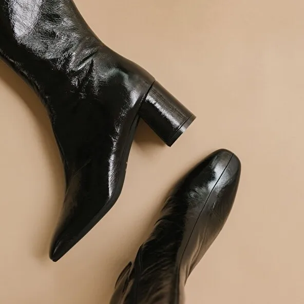 Heeled boots with pointed toe in black glazed leather